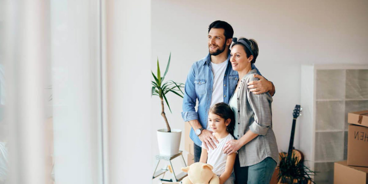 happy-family-looking-through-window-while-moving-into-new-home (1) (1)